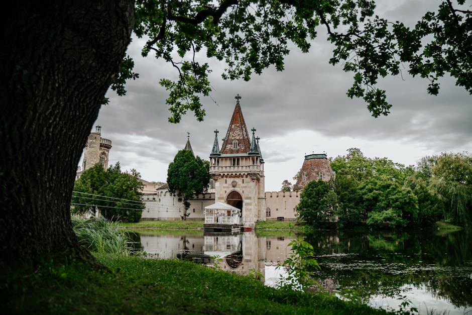 Scenic view of a medieval castle in Laxenburg, Austria, reflected in a tranquil lake surrounded by lush greenery.